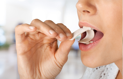 woman putting piece of gum into her mouth