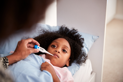 young girl getting her temperature taken with a thermometer