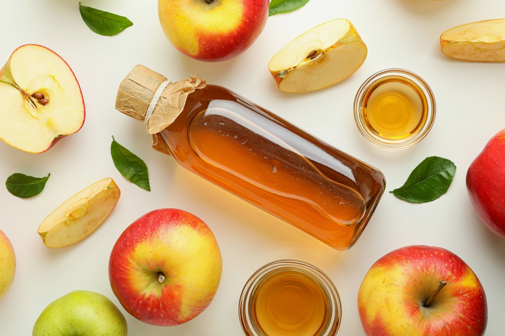 apple cider vinegar bottle surrounded by apples