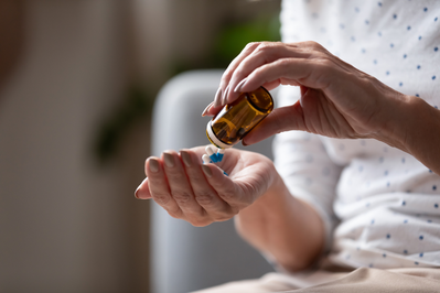 older woman pouring pills out of bottle into hand