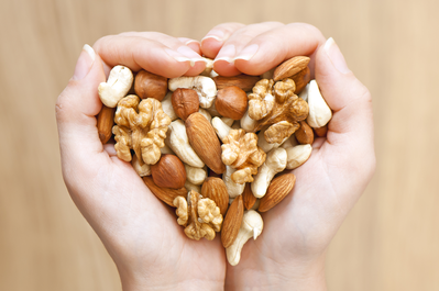 hands holding an assortment of nuts in a heart shape