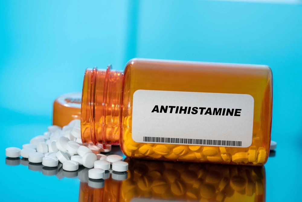 white pills spilling from bottle labeled Antihistamine