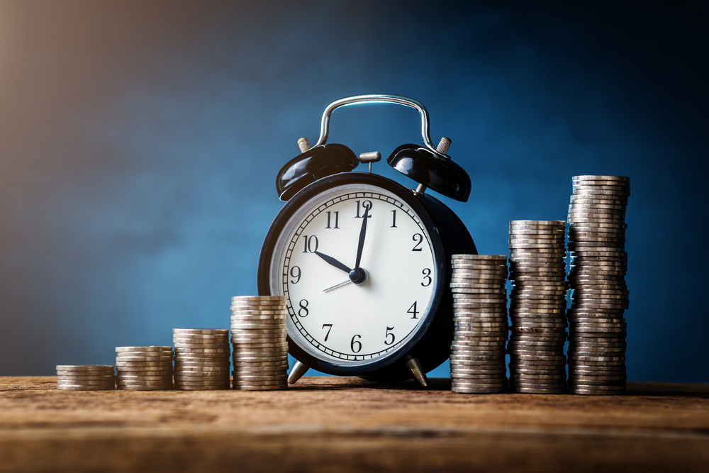 stacks of coins and alarm clock representing time and money